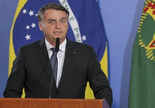 presidente Bolsonaro discursando com bandeira do Brasil atrás